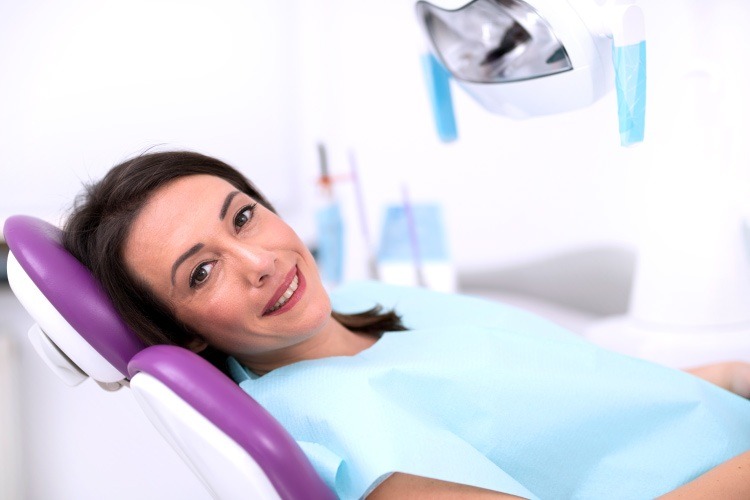 Smiling brunette woman in dental chair waiting for a dental implant