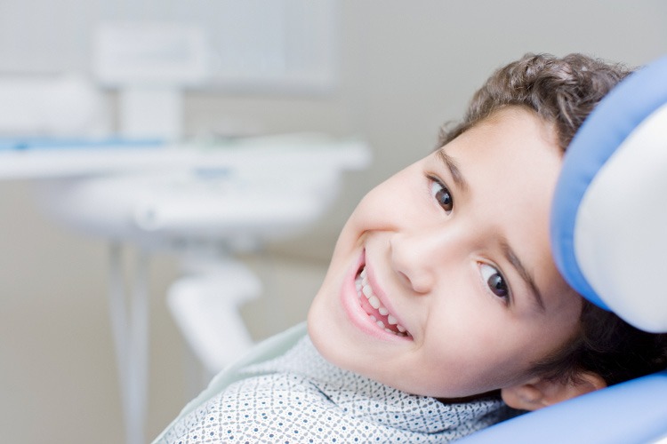 Smiling dark haired young boy in a dental chair