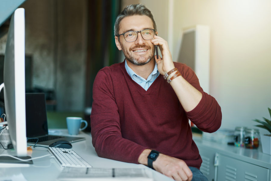 Smiling man on the phone in his home office