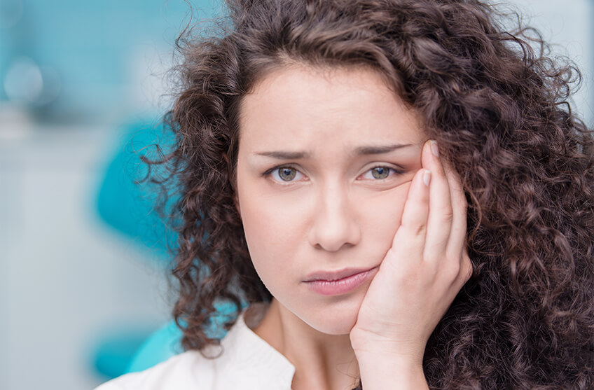 woman holding her hurting mouth