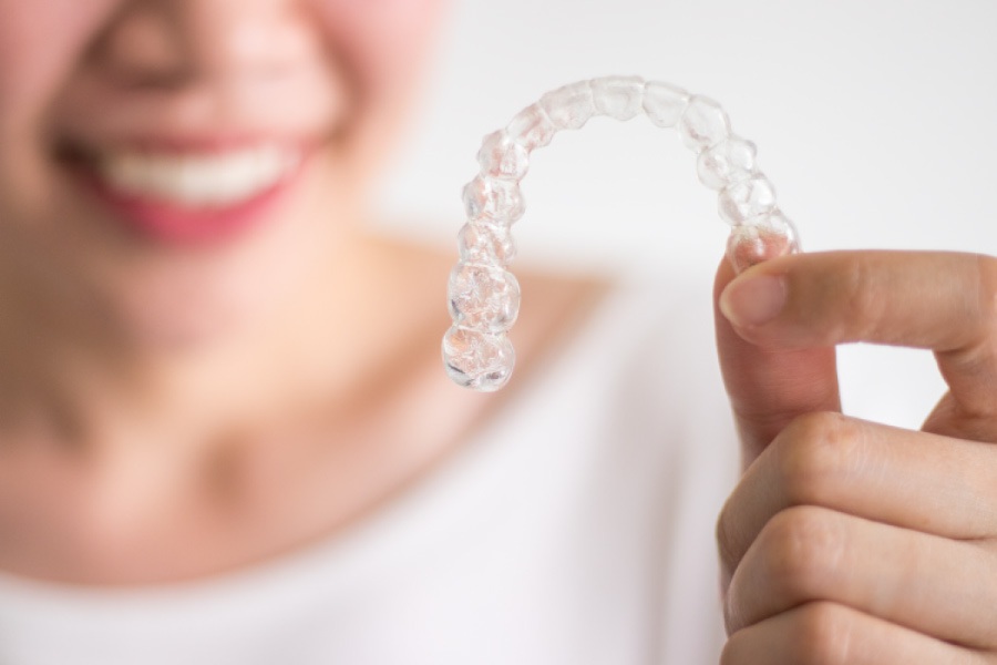 Woman holding an Invisalign clear aligner.