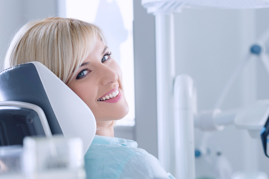 Smiling blond woman in the dental chair for a dental examination.