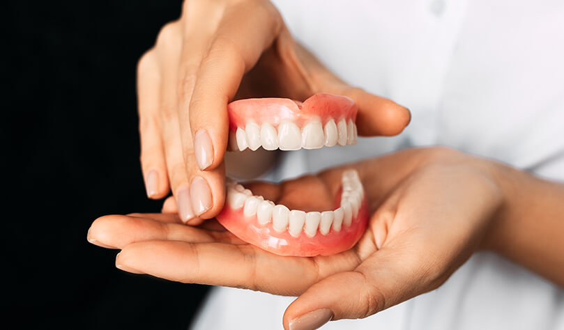 closeup of a person holding a set of dentures