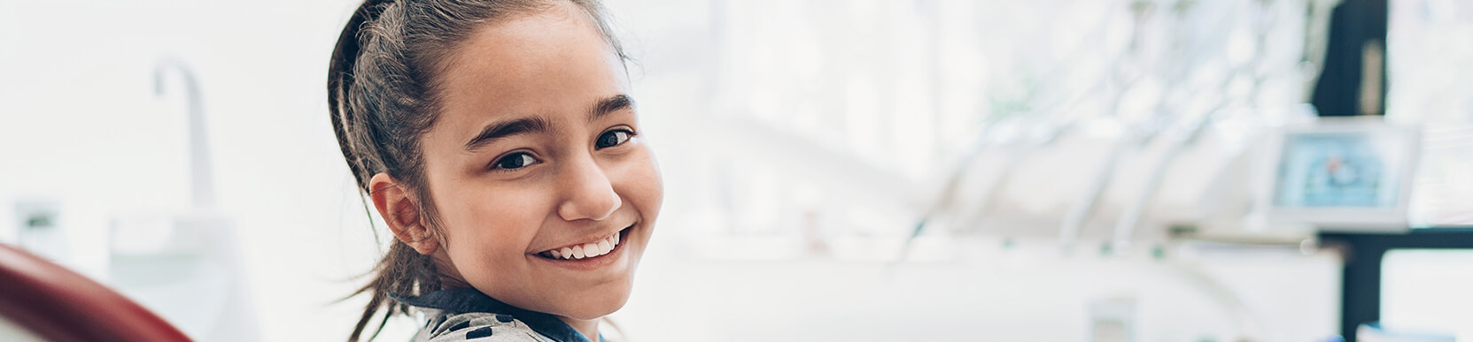 smiling young girl sitting in a dental chair