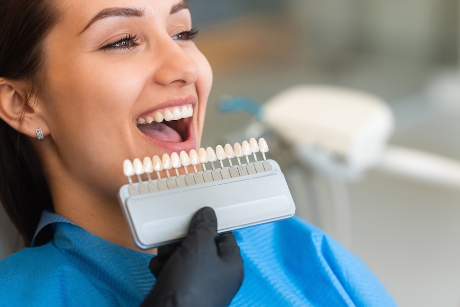 woman choosing a teeth whitening shade with a shade guide at the dentist
